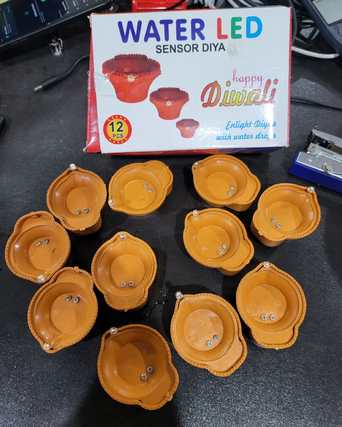 The "Water LED SENSOR DIYA (12PC BOX)" is a set of 12 LED diyas designed for decorative and celebratory purposes. These LED diyas are intended to replicate the traditional oil lamps, or diyas, commonly used in Indian festivals and cultural events. What makes them unique is the water sensor feature, which means that they illuminate when they come into contact with water. This feature offers a safe and convenient way to enjoy the warm and inviting glow of diyas without the use of an open flame. These LED diyas come in a box containing 12 units and are commonly used to add a festive and spiritual ambiance to various occasions, particularly during festivals like Diwali.